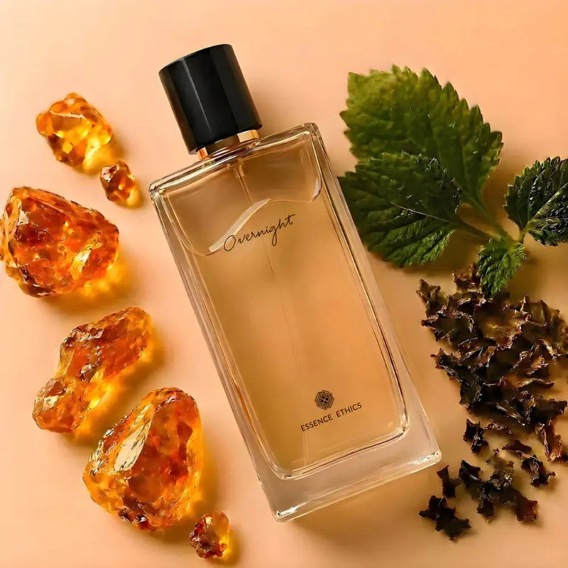 Perfume bottle labeled 'Overnight' by Essence Ethics with amber stones and green leaves on a beige background