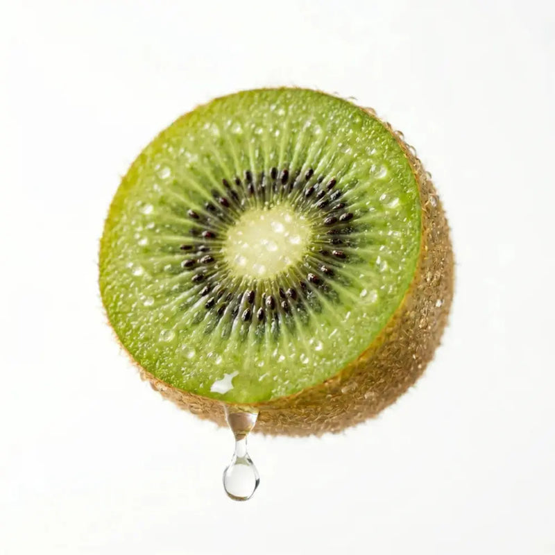 Sliced kiwi fruit with a droplet of juice on a white background